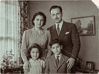 Fotografía en blanco y negro vintage deteriorada de una familia posando en el salón de su casa