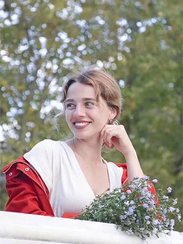 Fotografía original de mujer sonriendo con ramo de flores al aire libre con matiz verdoso general
