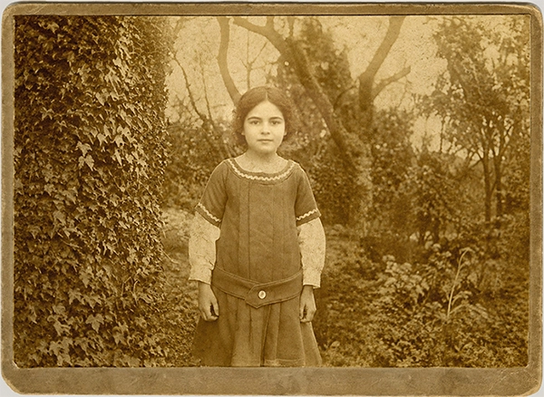 Antigua fotgrafía de una niña posando en un bosque con árboles