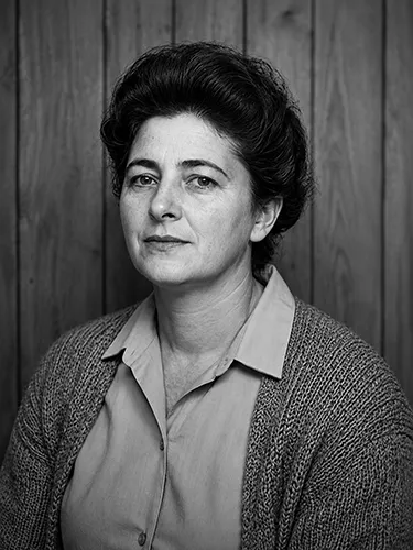 Retrato en blanco y negro restaurado de una mujer con camisa y chaqueta de punto.