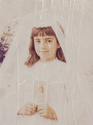 Foto de comunión antigua muy agrietada y dañada que muestra a una niña sosteniendo una estampa.