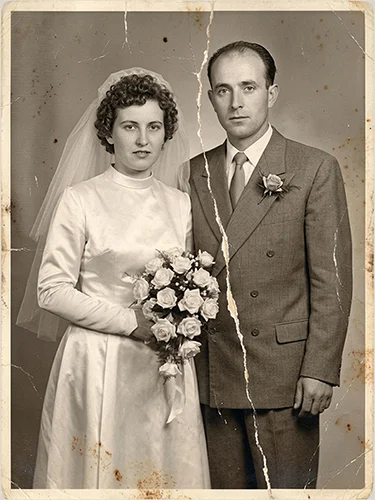 Foto de boda antigua muy dañada con una gran rasgadura vertical en el centro.