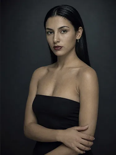 Plano medio de una mujer con el cabello hacia atrás, pendientes dorados y top sin tirantes negro.