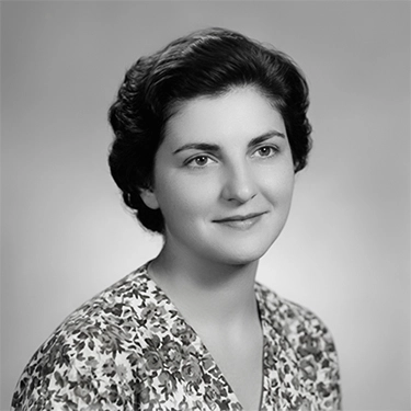 Retrato restaurado en blanco y negro de una mujer joven sonriente con blusa estampada de flores.